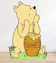 a cartoon bear sitting on the ground next to a honey pot and holding it up