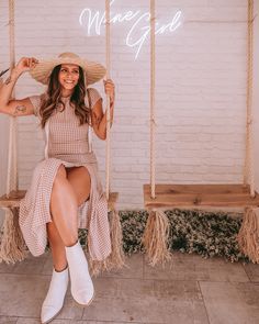 a woman sitting on a swing wearing a straw hat and white boots with the words whineggie written above her