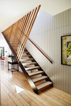 a wooden stair case next to a painting on the wall