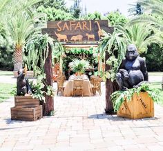 an outdoor dining area with gorilla statues, palm trees and wooden crates on the ground