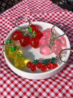 fruit keychains are sitting in a bowl on a red and white checkered tablecloth