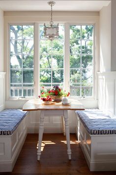 a table with two benches and a bowl of fruit on it in front of a window