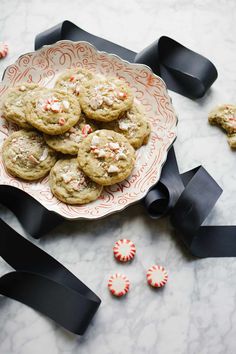 chocolate chip cookies and candy canes on a plate with black ribbon next to them