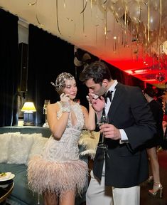 a man in a tuxedo standing next to a woman wearing a feathered dress