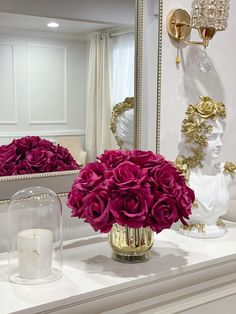 flowers in a vase sitting on top of a counter next to a mirror and candle holder