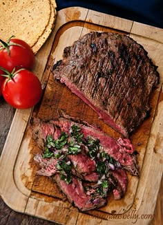 steak and tomatoes on a cutting board next to tortilla chips