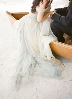 a bride and groom sitting in a canoe on the beach