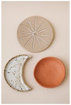 two ceramic moon and plate sitting next to each other on top of a white surface