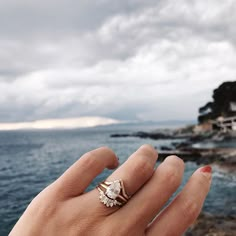 a woman's hand with a ring on it near the ocean