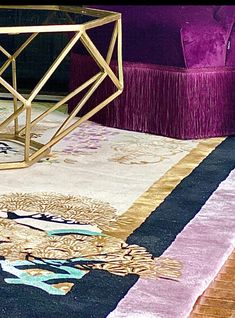 a purple chair sitting on top of a wooden floor next to a rug with an intricate design