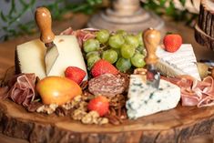 an assortment of cheeses and fruits on a wooden platter