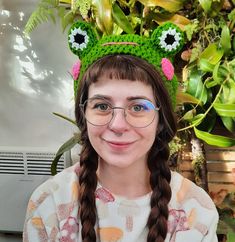 a girl with glasses and a green frog hat