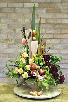 an arrangement of flowers on a table with a brick wall in the backround