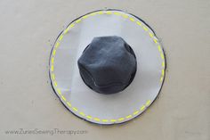 a black hat sitting on top of a white and yellow circular plate covered in paper