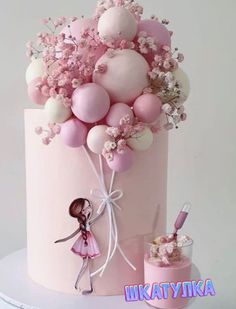 there is a pink cake with balloons on it