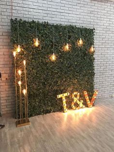 a man standing in front of a green wall with lights on it and the word love spelled out