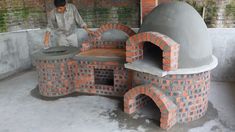 a man standing next to an outdoor brick pizza oven in the middle of a building