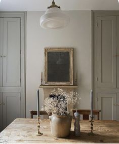 a wooden table topped with a potted plant next to a chalkboard and candles