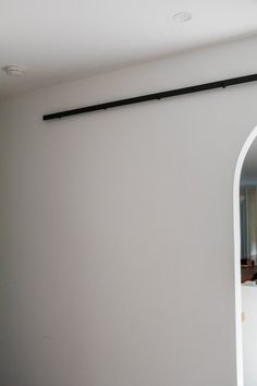 an arched window in a white room with a mirror on the wall and light fixture above it