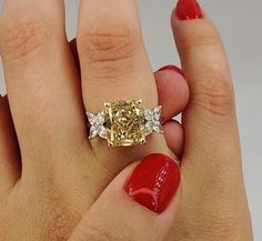 a woman's hand holding a yellow diamond ring