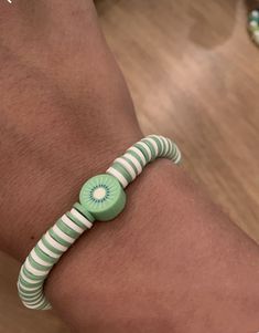 a person wearing a green and white striped bracelet with a button on the end of it