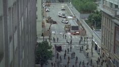 an aerial view of people walking on the street in front of tall buildings and traffic