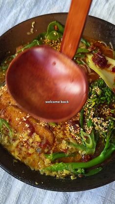 a pan filled with broccoli and other vegetables being stirred by a wooden spoon