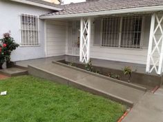 a white house with steps leading up to the front door and flowers on the lawn