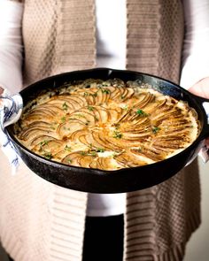 a person holding a dish with potatoes in it