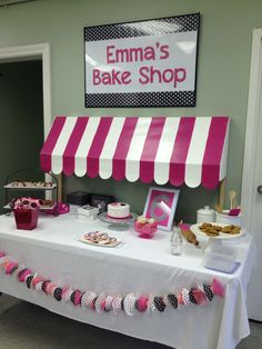 a pink and white striped awning over a table filled with cakes, pastries and desserts