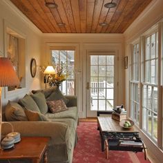 a living room filled with furniture and windows next to a red carpeted flooring