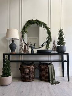 a black table topped with potted plants next to a mirror and two wicker baskets