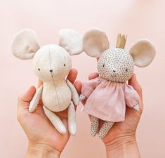 two handmade stuffed animals are held in front of a pink wall with polka dots