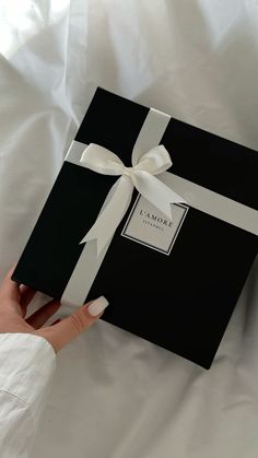 a woman's hand holding a black and white gift box