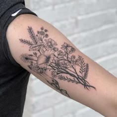 a woman's arm with flowers and leaves tattooed on the left side of her arm