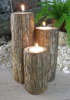 three wooden logs with lit candles in them