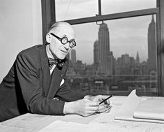 an old man sitting at a desk in front of a window looking at his cell phone