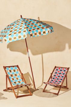 two lawn chairs and an umbrella in front of a wall