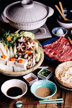 a table topped with lots of different types of food and bowls filled with sauces