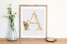 a cross stitch pattern with a bear and flowers in front of a vase on a table