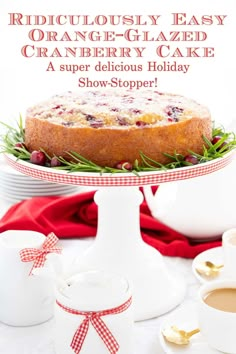 a cake sitting on top of a white plate next to cups and saucers with the words ridiculously easy orange - glazed cranberry cake