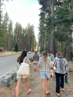 four girls are walking down the dirt road