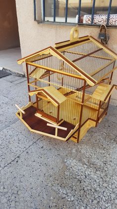 a bird cage sitting on the ground next to a building