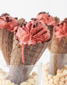 three cones filled with ice cream sitting on top of a table next to white chocolate chips