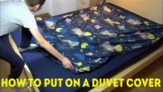 a man is placing an outer space themed sheet on a bed