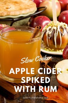 an apple cider spied with rum in front of some apples and cinnamon sticks