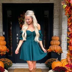 a woman standing in front of a door wearing a green dress and brown cowboy boots