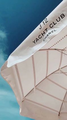 a white umbrella with the words yacht club on it and blue sky in the background