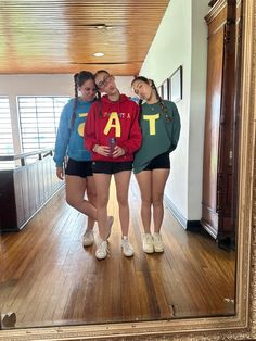 three girls standing in front of a mirror with their arms around each other's shoulders