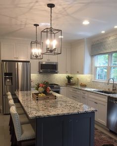 a large kitchen with an island in the middle and lots of lights hanging from the ceiling